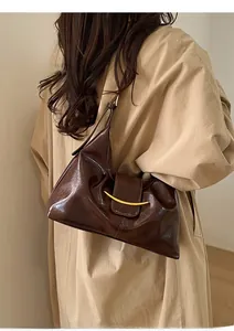 Détail du sac à bandoulière en cuir huilé marron avec boucle en métal doré en croissant