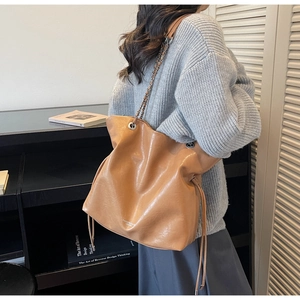 Close-up of caramel vintage tote with metal chain strap and white printed logo detail