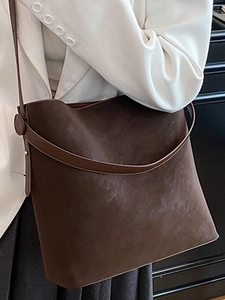 Borsa a secchiello in pelle scamosciata marrone scuro indossata da una modella