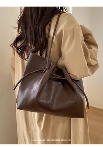 Detail of dark brown tote bag with retro drawstring knot and smooth leather texture