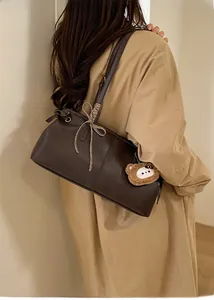 Detail of dark brown tote bag featuring a leather texture and a cute plush bear pendant