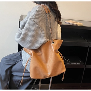 Brown leather tote bag featuring a metal chain strap and logo detail on side