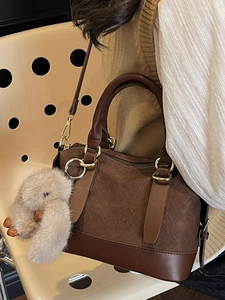 Brown woven texture tote bag with golden hardware and plush bunny charm on a model