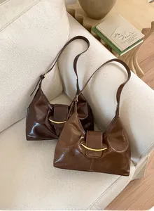 Détail du sac bandoulière en cuir huilé vintage avec boucle dorée en croissant et texture riche