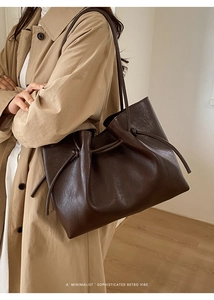 Detail of a dark brown retro leather tote bag with unique side knot design and soft texture