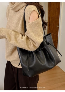 Chic black leather tote bag featuring a decorative side drawstring knot and retro style