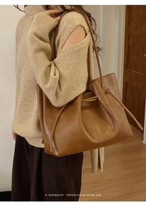 Detail of a large brown retro tote bag with drawstring folds worn by a model