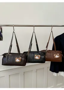 Three vintage leather tote bags in brown, black, and caramel with bear charms and bow detail