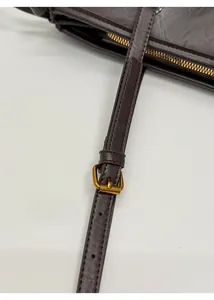 Detail of deep brown leather shoulder strap with adjustable golden buckle and stitching