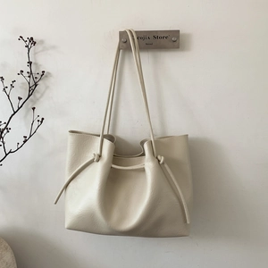 Detail of a minimalist cream white tote bag with knotted strap and leather texture