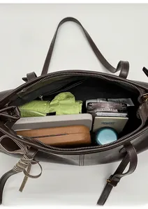 Top view of spacious brown leather tote interior with daily essentials and silk scarf detail