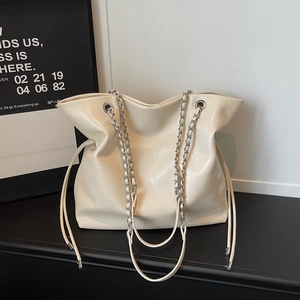 Close-up of cream leather tote with chain straps and drawstring closure detail