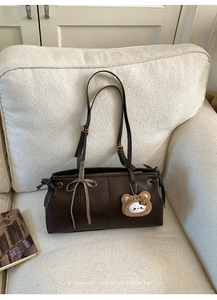Detail of dark brown vintage faux leather shoulder bag with cute ribbon and plush charm
