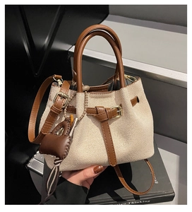 Detail of canvas bucket bag with brown leather trim and retro buckle strap design