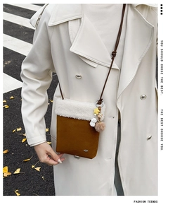 Detail of brown suede crossbody bag with white faux fur trim and cute star charms