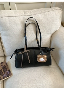 Detail of retro black leather tote bag with plaid bow and cute teddy bear charm