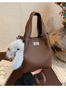 Detail of lychee pattern leather bucket bag with silver metal twist lock and plush charm