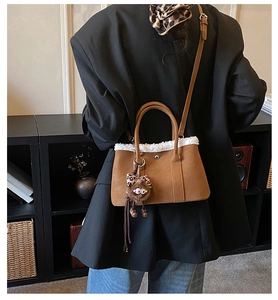 Détail du sac cabas en daim marron avec bordure en peau lainée et breloque léopard