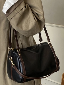 Vintage black Boston pillow bag with brown leather straps shown on a beige trench coat