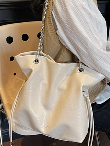 Chic cream white leather tote bag with silver chain strap and drawstring closure