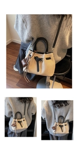Close-up of beige woven bucket bag with heart pendant and adjustable leather strap