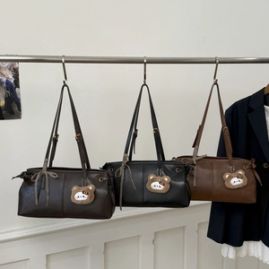 Close-up of three leather tote bags in brown and black with bear charms and bow detail
