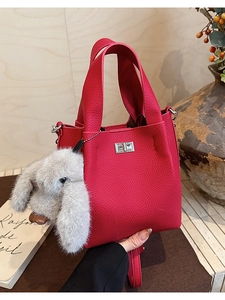 Detail of fuchsia bucket bag showing lychee grain leather and fluffy rabbit charm