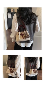 Detail of woven fabric bucket bag with burgundy leather trim and branded bag charm