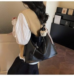 Détail du sac cabas en cuir noir avec fermetures éclair et un charmant petit ours en peluche
