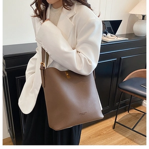 Detail of adjustable strap and golden turn-lock closure on brown litchi leather bag
