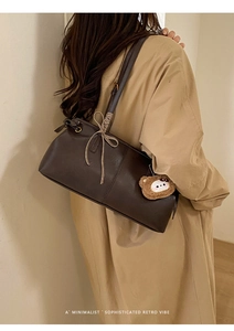Detailed view of coffee brown faux leather shoulder bag with plush bear charm and bow decoration