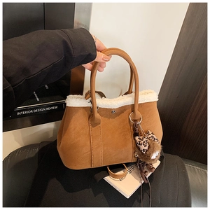 Détail du sac à main en daim marron avec bordure en fausse fourrure et nœud léopard