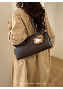 Detail view of dark brown retro shoulder bag with plush bear charm and adjustable strap