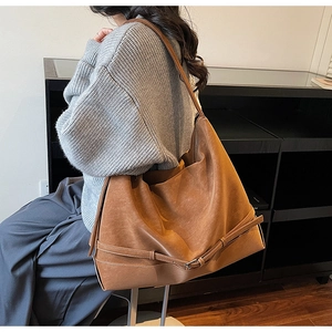 Dettaglio di una grande borsa tote in ecopelle marrone con fibbia vintage su modella