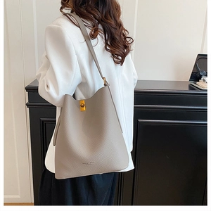 Detailed close-up of gray lychee texture leather bucket bag with gold turn-lock closure