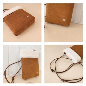 Detail view of caramel suede crossbody bag featuring white faux shearling trim and metal plaque