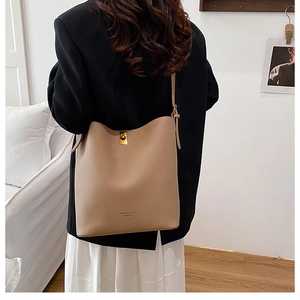 Detail of lychee pattern leather shoulder bag showing gold metal buckle and brand logo