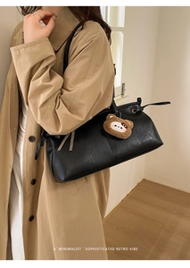 Close-up of black retro tote bag with matte leather finish and brown plush bear charm