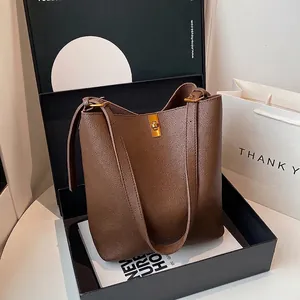 Detail of brown litchi pattern leather bucket bag with gold lock and adjustable strap