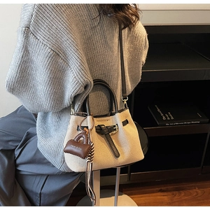 Detail showing canvas bucket bag with leather trim and mini purse charm on a model