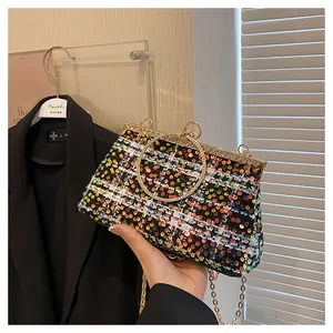 Close-up of elegant sequin handbag with gold circular ring handle and diamond trim