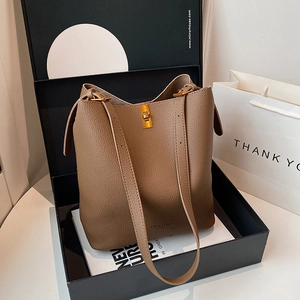 Close-up of brown lychee grain leather bucket bag with gold metal twist lock in gift box