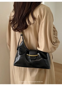 Vue latérale du sac à bandoulière en cuir ciré noir avec boucle dorée sur modèle