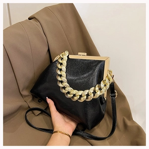 Detailed shot of black pebbled leather handbag with chunky gold chain and metal frame