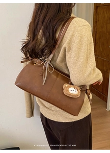 Close-up of brown leather tote bag with ribbon bow and cute plush bear accessory