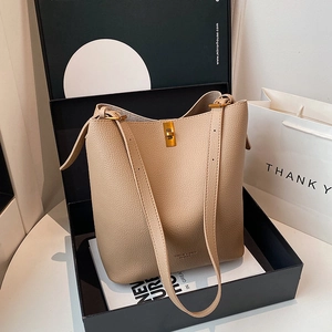Close-up of beige leather bucket bag with gold clasp and brand logo in a luxury gift box