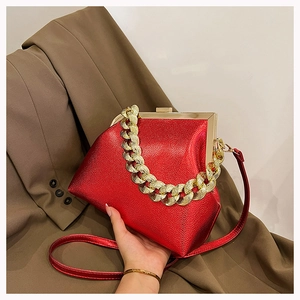 Close-up of red lychee pattern leather bag with golden chain and metal frame closure