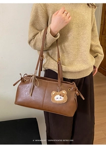Close-up of brown retro tote bag featuring side bow ties and a cute plush bear pendant