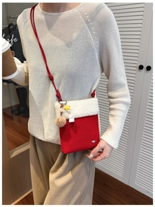 Detail of a red and white plush crossbody bag with festive charms on a model