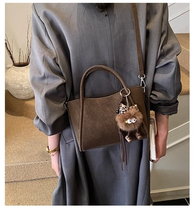 Close-up of brown vintage bucket bag with leopard bow charm on a leather handle